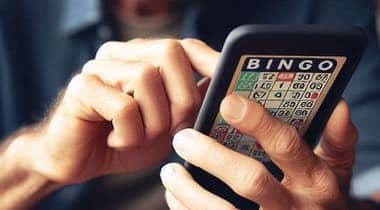En man som håller i en mobil med ett mobilskal med en bingobricka på.
