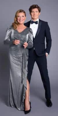 Programledarna i Bingolottos nyårsbingo. Lotta Enberg i glittrig festklänning i silver och Daniel Norberg i svart kostym, vit skjorta och fluga.