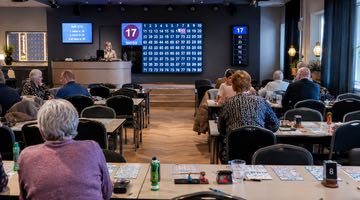 En bingohall där människor sitter och spelar bingo